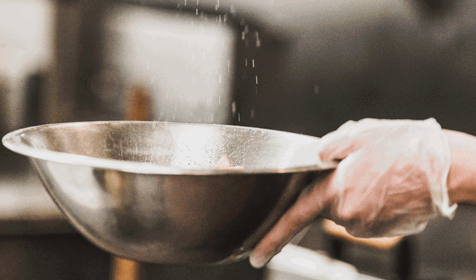 Hand strör salt i en skål